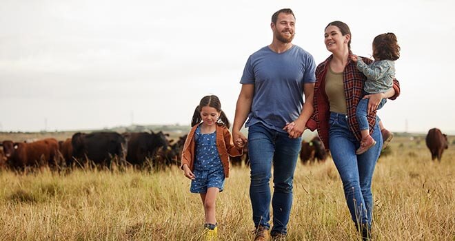 farm family walking through a field cows in the background